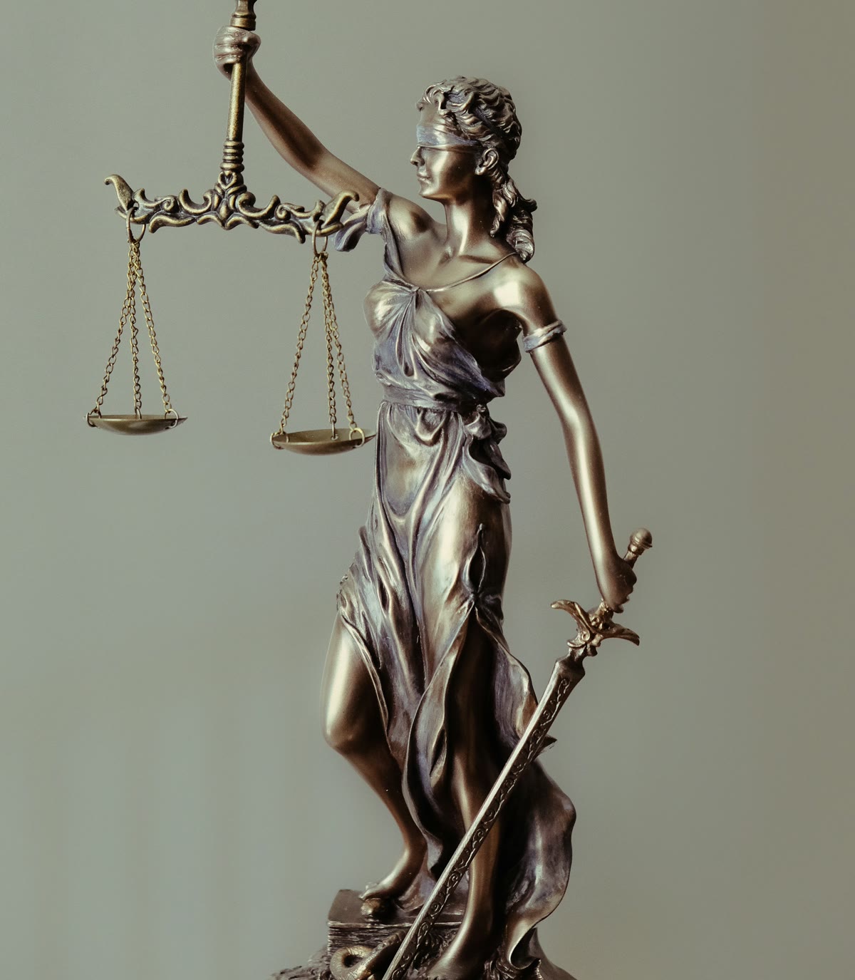 A bronze statue of Lady Justice holding balanced scales