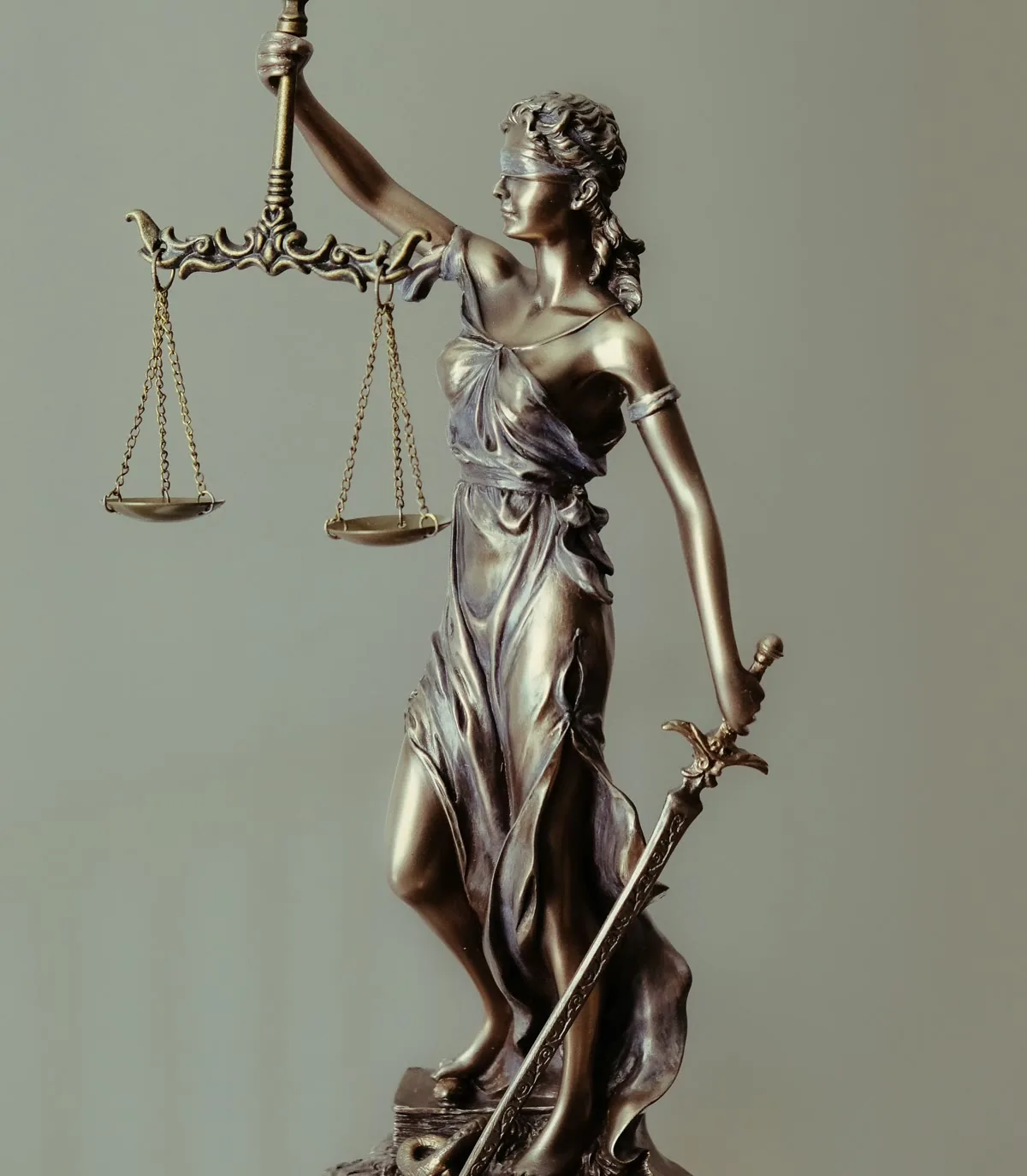 A bronze statue of Lady Justice holding balanced scales